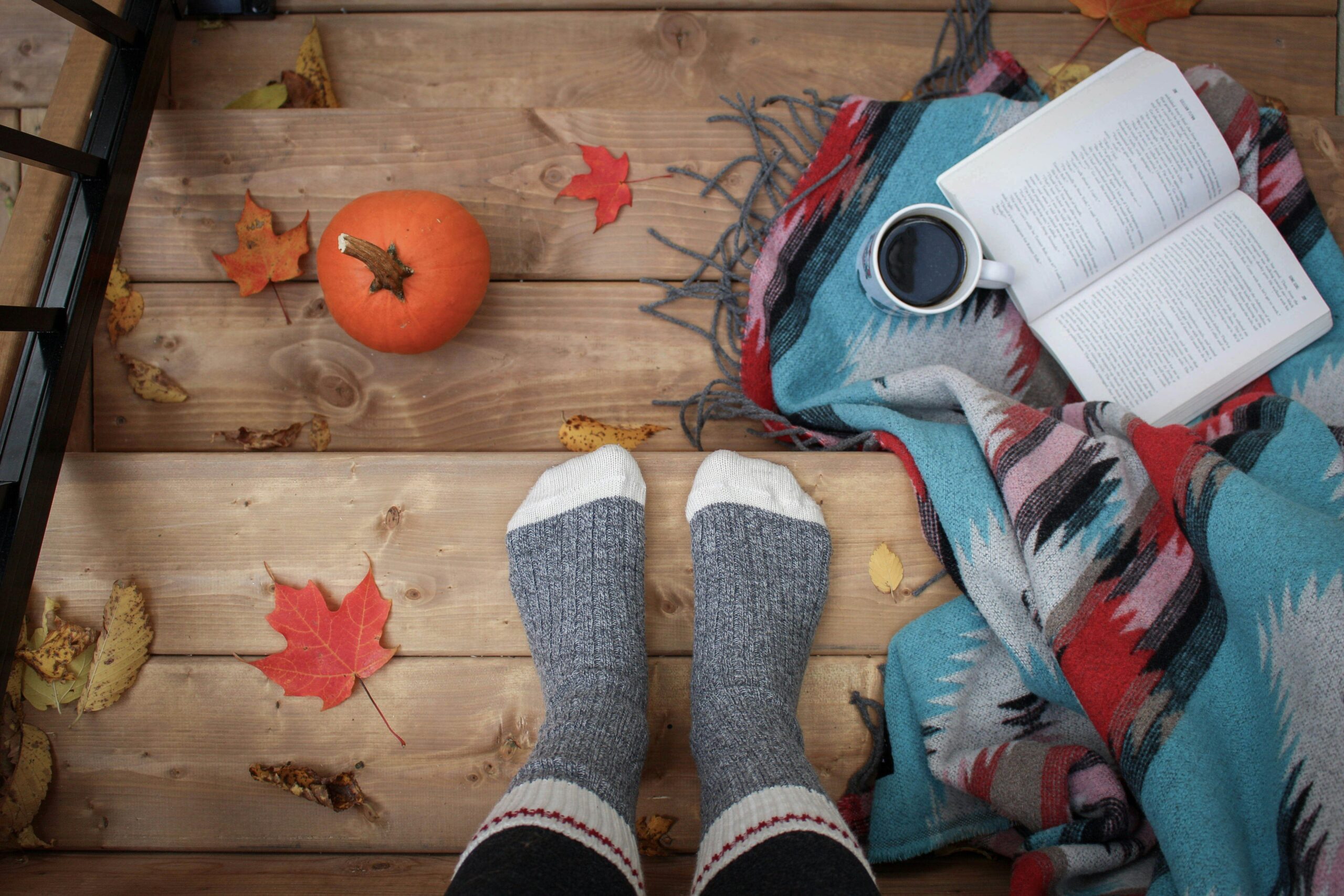 "Personne en chaussettes lisant un livre avec une citrouille, illustration de l'automne et de la créativité DIY pour le bien-être - Box Hello Kit, loisirs créatifs France"