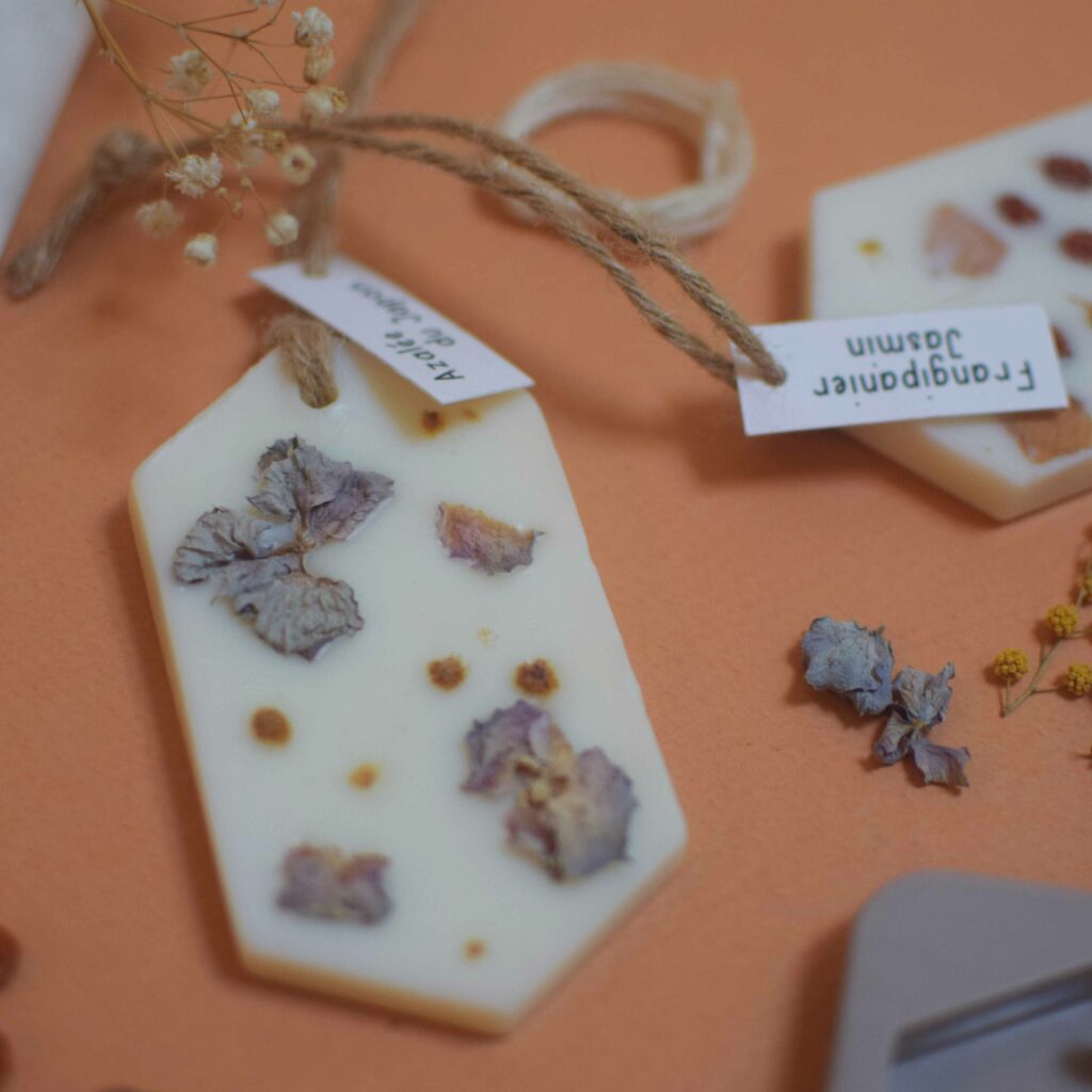 Kit DIY suspension parfumée avec moule en silicone, fleurs séchées, cire végétale, parfum de Grasse et étiquettes, sur fond terracotta.